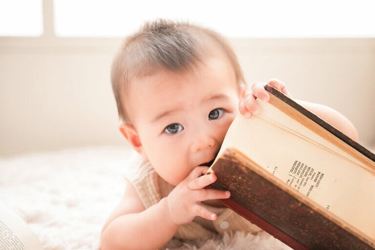 ハーフバースデーの赤ちゃんが本をかじってる